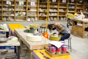 woman molding clay on the wheel in the clay studio at VisArts
